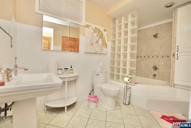 bathroom with tile patterned flooring, tile walls, toilet, and tiled shower / bath