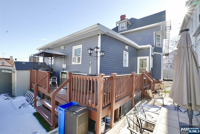 snow covered rear of property with a wooden deck