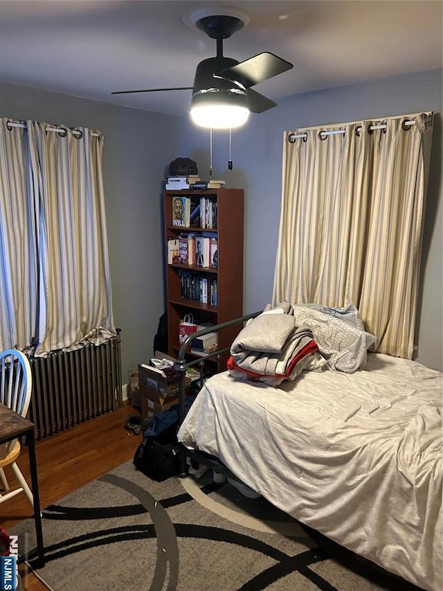 bedroom with radiator, wood-type flooring, and ceiling fan