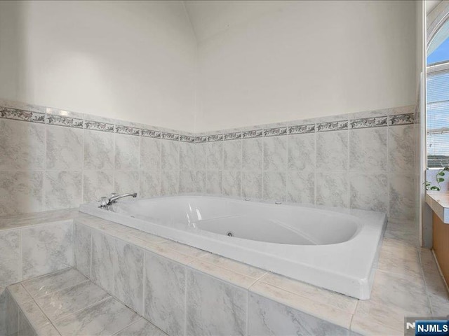 bathroom featuring vanity and tiled tub