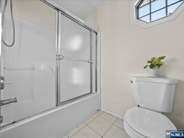 bathroom featuring tile patterned floors, enclosed tub / shower combo, and toilet