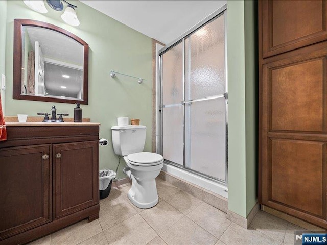 bathroom featuring tile patterned floors, toilet, a shower with shower door, and vanity