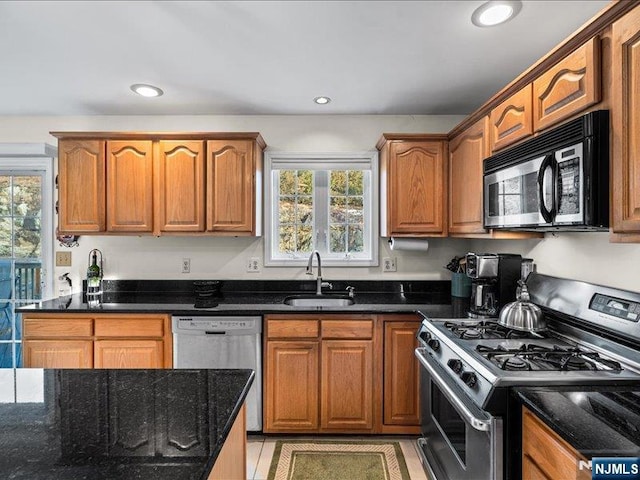 kitchen with sink, dark stone counters, and appliances with stainless steel finishes