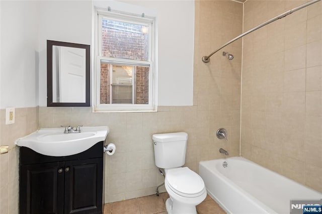 full bathroom with tile patterned floors, toilet, tiled shower / bath, tile walls, and vanity