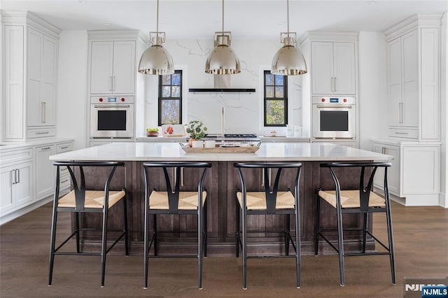 kitchen featuring a breakfast bar area, oven, and a large island with sink