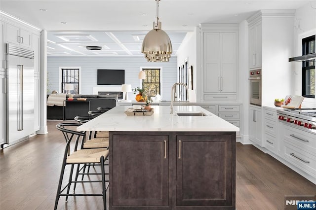 kitchen with a kitchen bar, sink, decorative light fixtures, a center island with sink, and stainless steel appliances