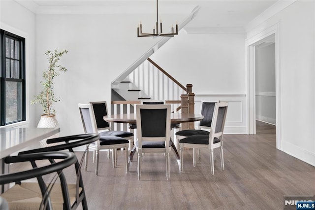 dining space with an inviting chandelier, wood-type flooring, and ornamental molding