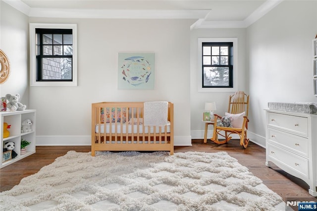 bedroom featuring a nursery area, ornamental molding, and dark hardwood / wood-style flooring