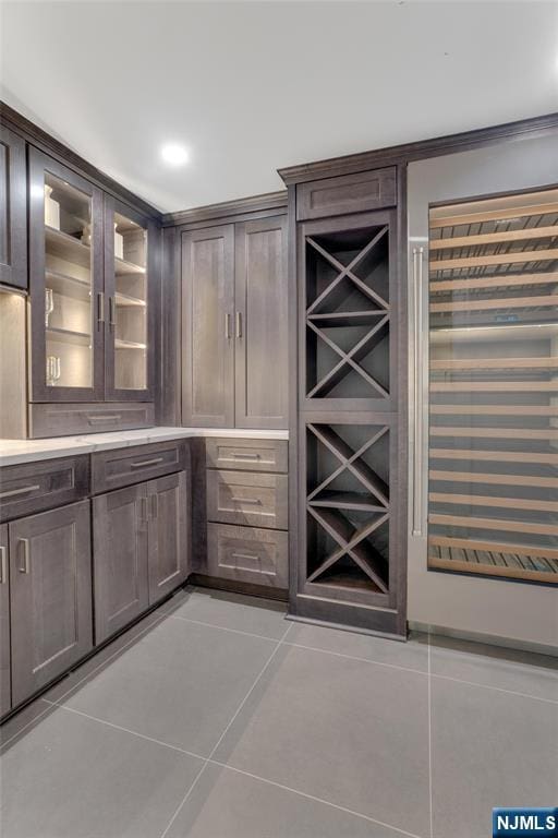 bar featuring light tile patterned flooring and dark brown cabinets