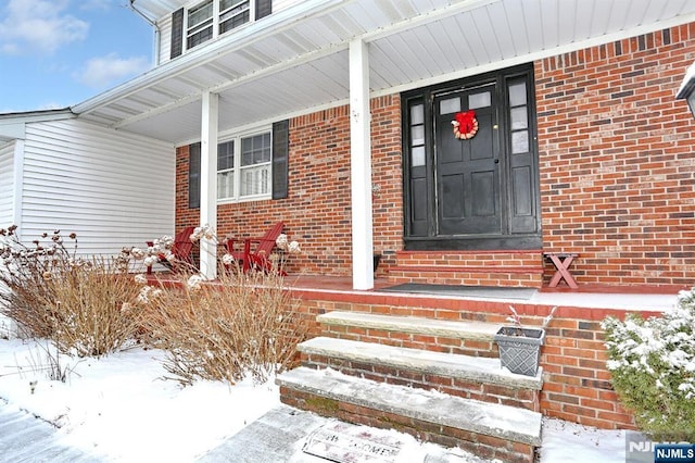 snow covered property entrance featuring covered porch