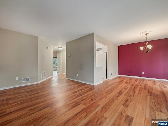 unfurnished room featuring an inviting chandelier and wood-type flooring