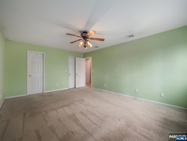 unfurnished bedroom featuring multiple closets, ceiling fan, and carpet floors