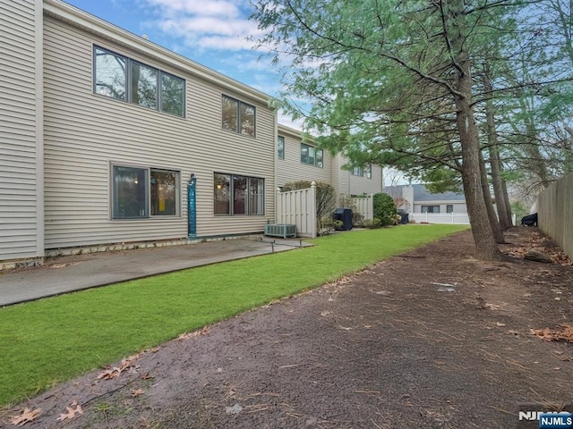 back of house featuring a yard and central air condition unit