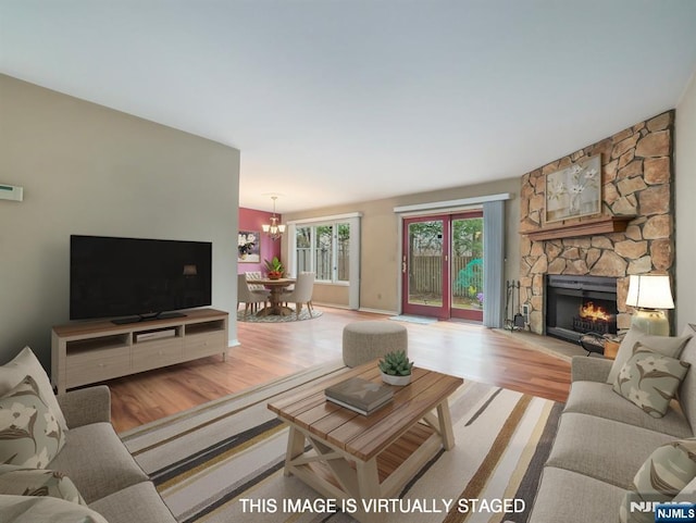 living room with a notable chandelier, a fireplace, and light wood-type flooring