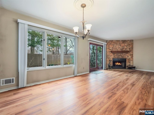 unfurnished living room with a fireplace, a notable chandelier, and light hardwood / wood-style flooring