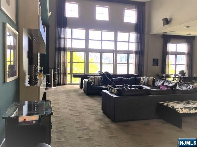 living room featuring a towering ceiling and carpet flooring