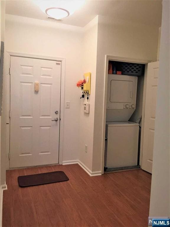 foyer entrance featuring stacked washer and dryer and dark wood-type flooring