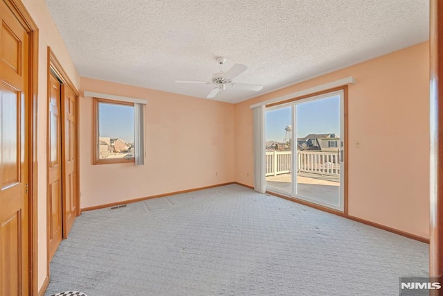 empty room with ceiling fan, light carpet, and a textured ceiling