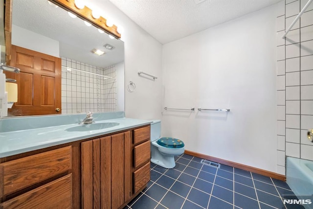 full bathroom featuring tiled shower / bath, vanity, toilet, tile patterned floors, and a textured ceiling