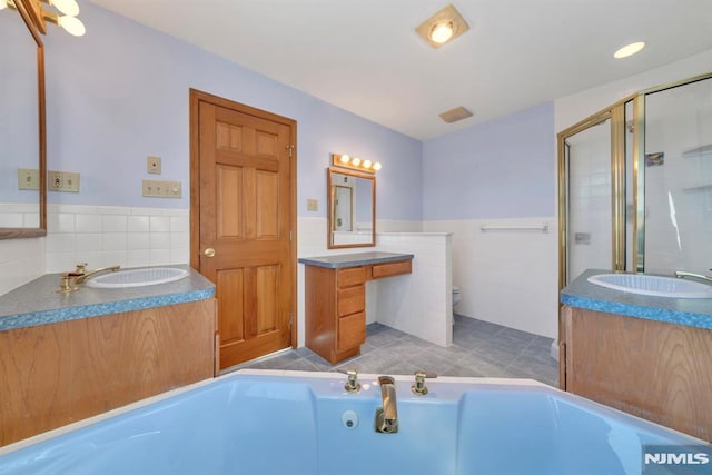 full bathroom with tile walls, tile patterned flooring, vanity, plus walk in shower, and toilet