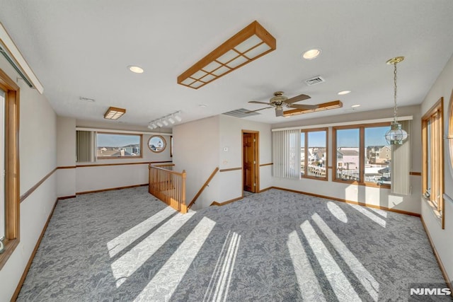 unfurnished living room with rail lighting and carpet floors