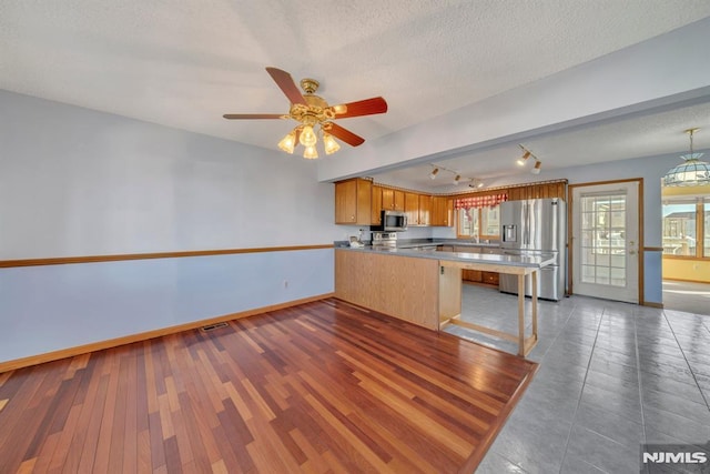 kitchen with dark hardwood / wood-style flooring, ceiling fan, kitchen peninsula, stainless steel appliances, and a textured ceiling