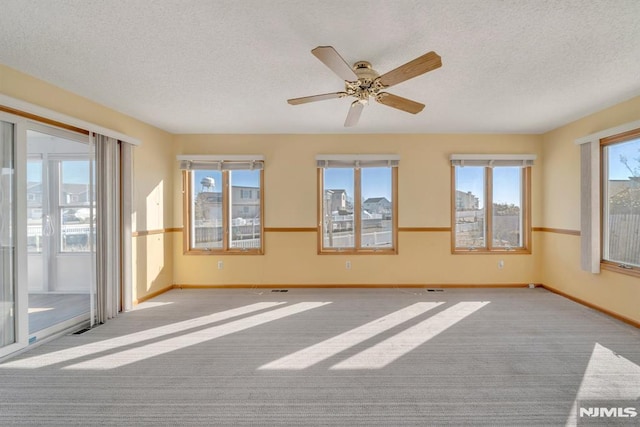 empty room with ceiling fan, light carpet, and a textured ceiling