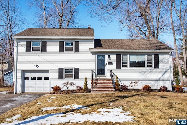 tri-level home with a garage and a lawn