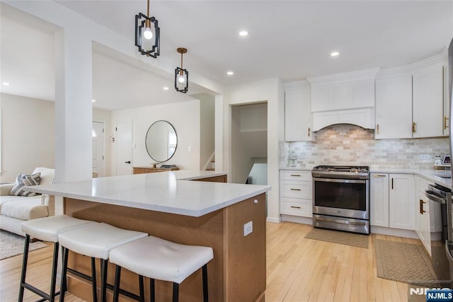 kitchen with hanging light fixtures, gas range, white cabinets, and a kitchen island