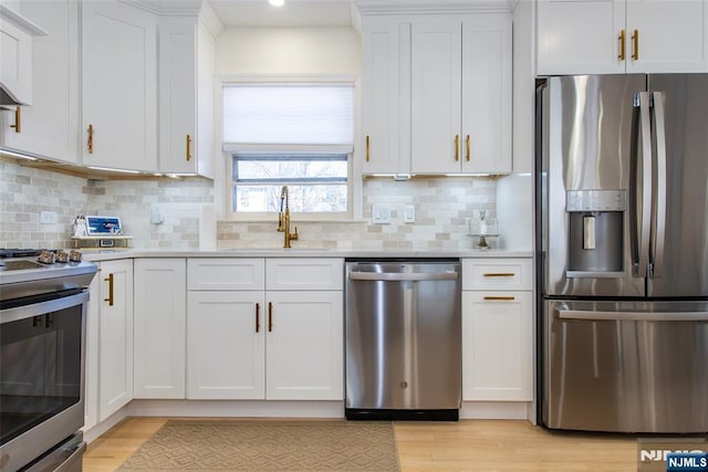 kitchen with stainless steel appliances, white cabinetry, sink, and light wood-type flooring