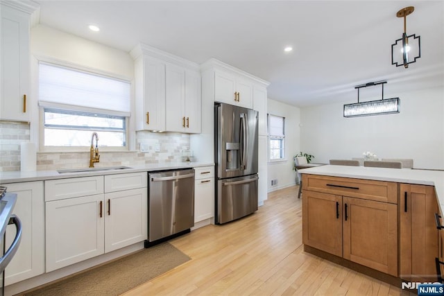 kitchen with sink, backsplash, stainless steel appliances, white cabinets, and decorative light fixtures