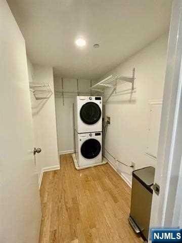 clothes washing area featuring stacked washer / dryer and light hardwood / wood-style floors