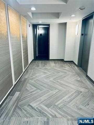 hallway with light parquet flooring and elevator