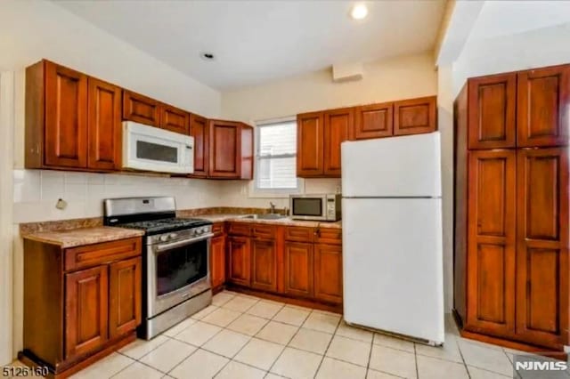 kitchen featuring stainless steel appliances, tasteful backsplash, a sink, and light tile patterned floors