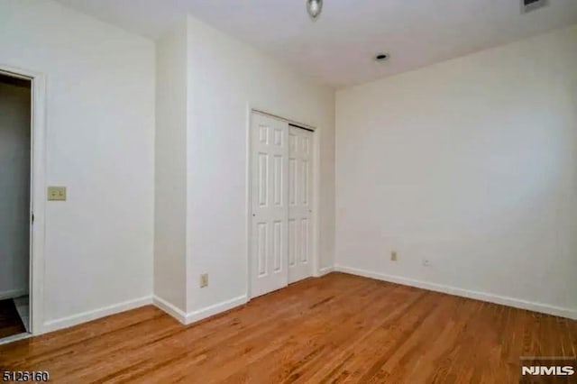 unfurnished bedroom with light wood-style floors, a closet, and baseboards