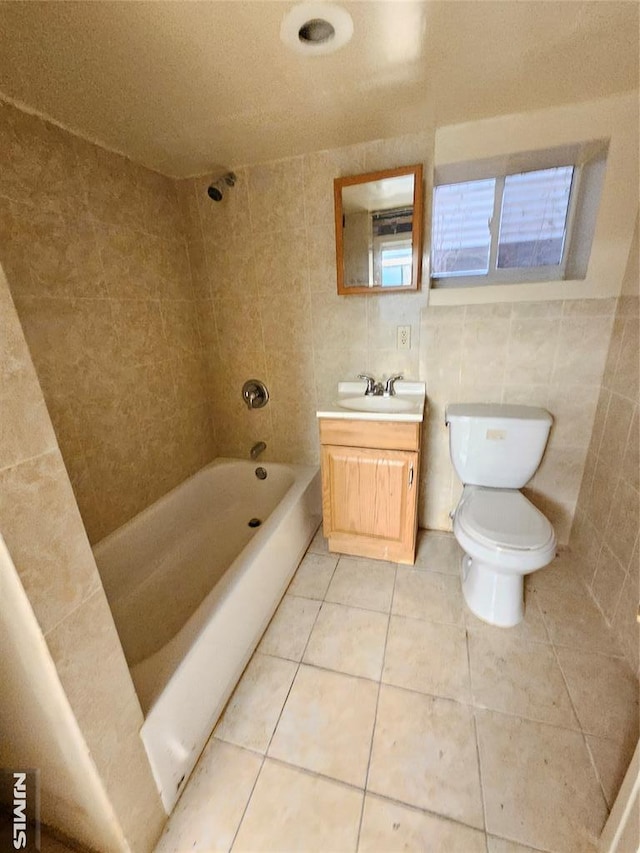 bathroom featuring shower / bath combination, toilet, tile patterned flooring, vanity, and tile walls