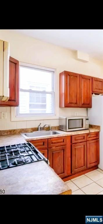 kitchen with brown cabinets, light countertops, a wealth of natural light, and light tile patterned flooring