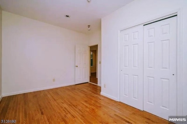 unfurnished bedroom with a closet, light wood-style flooring, and baseboards