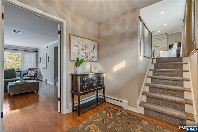 stairway with hardwood / wood-style floors, crown molding, and a baseboard radiator