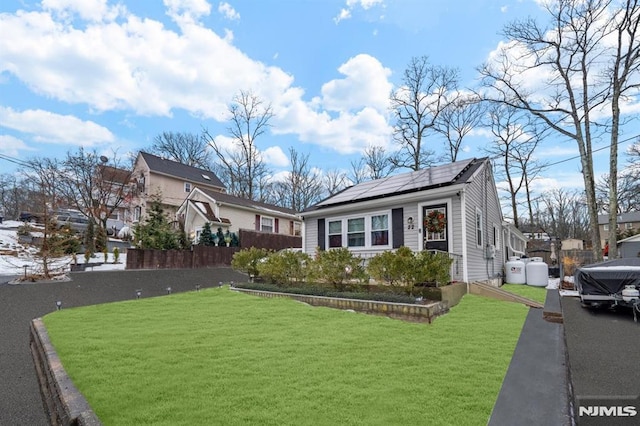 bungalow with a front lawn and solar panels