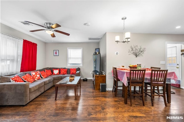 living room with ceiling fan with notable chandelier and dark hardwood / wood-style flooring