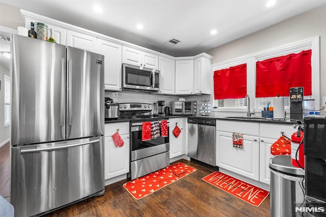 kitchen featuring dark hardwood / wood-style floors, tasteful backsplash, sink, white cabinets, and stainless steel appliances