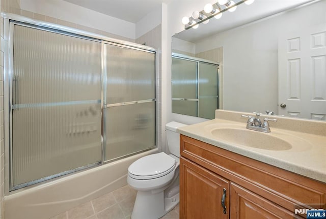 bathroom featuring tile patterned flooring, combined bath / shower with glass door, vanity, and toilet