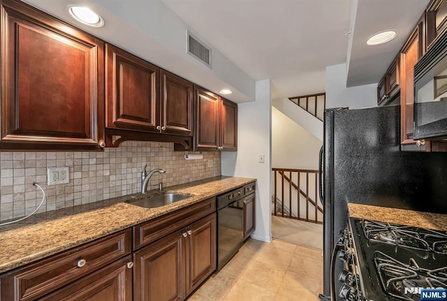 kitchen with a sink, visible vents, light stone countertops, black appliances, and tasteful backsplash