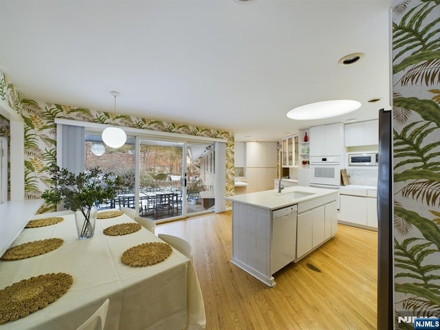 kitchen featuring white appliances, a sink, decorative light fixtures, and white cabinets