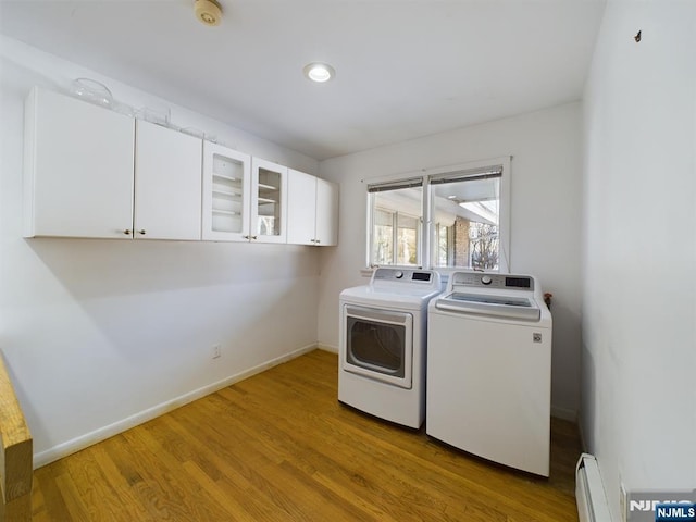 laundry area with a baseboard radiator, washing machine and dryer, baseboards, cabinet space, and light wood finished floors