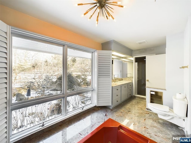 bathroom with a notable chandelier, vanity, and toilet