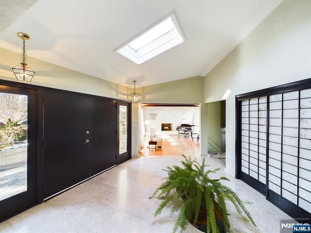 foyer featuring vaulted ceiling with skylight and light floors