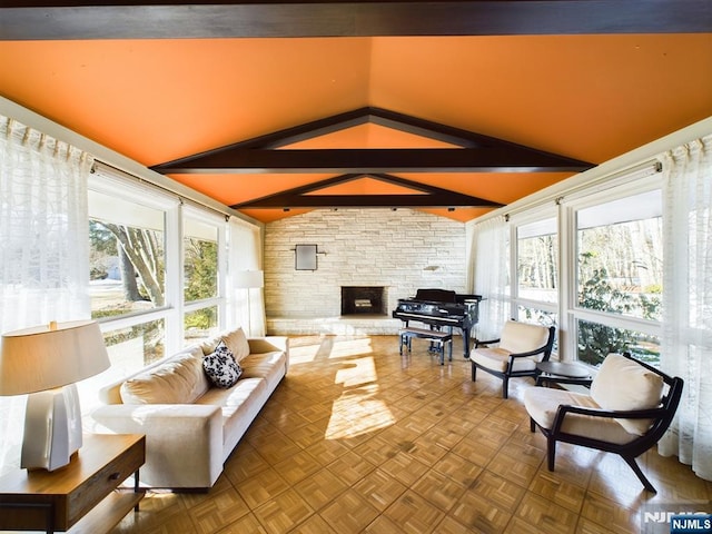 sunroom / solarium with a stone fireplace, a healthy amount of sunlight, and lofted ceiling with beams