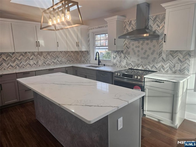 kitchen with dark hardwood / wood-style flooring, wall chimney range hood, decorative light fixtures, and sink